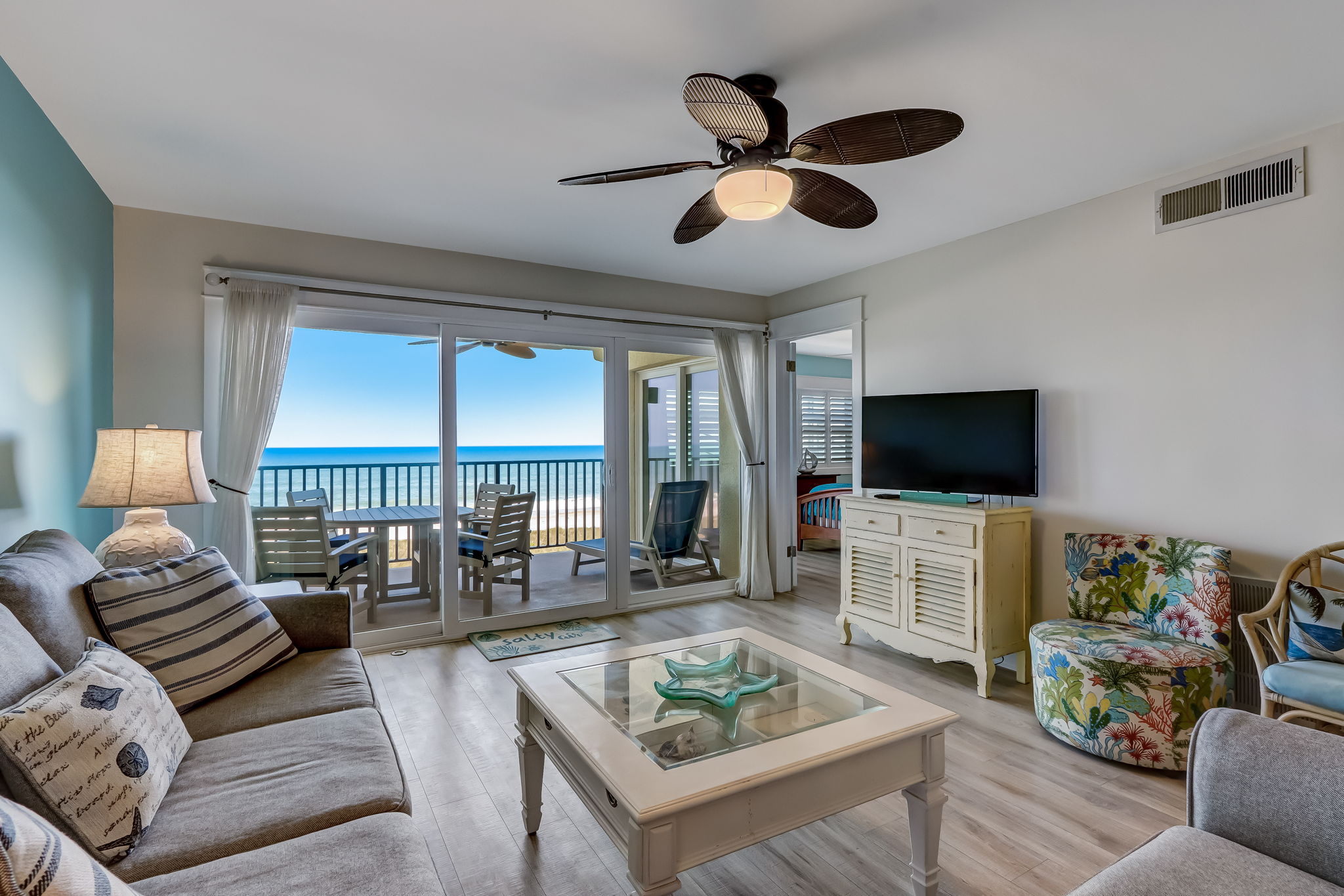 Living room with palm-blade fan and ocean view balcony